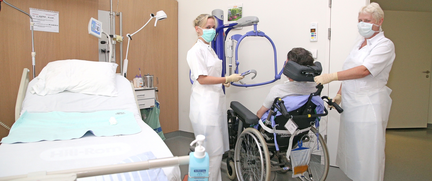 Pflegerinnen betreuen Mann im Rollstuhl