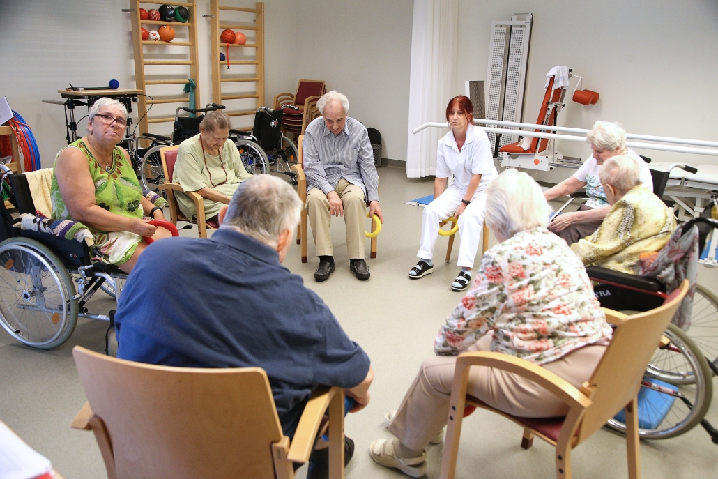 Ältere Bewohner im Sesselkreis und therapeutischer Untestüztung