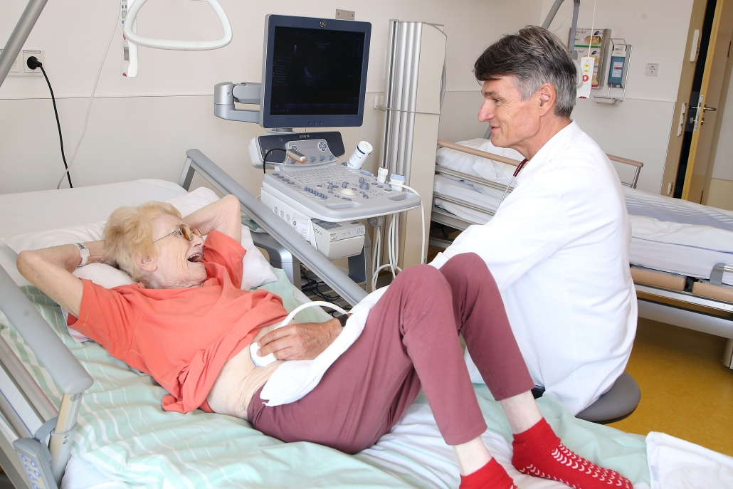 Ältere Patientin wird von Arzt im Bett untersucht