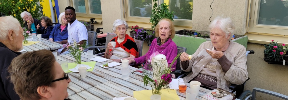 PFL mehrere BewohnerInnen bei der Jause im Garten WIGEV