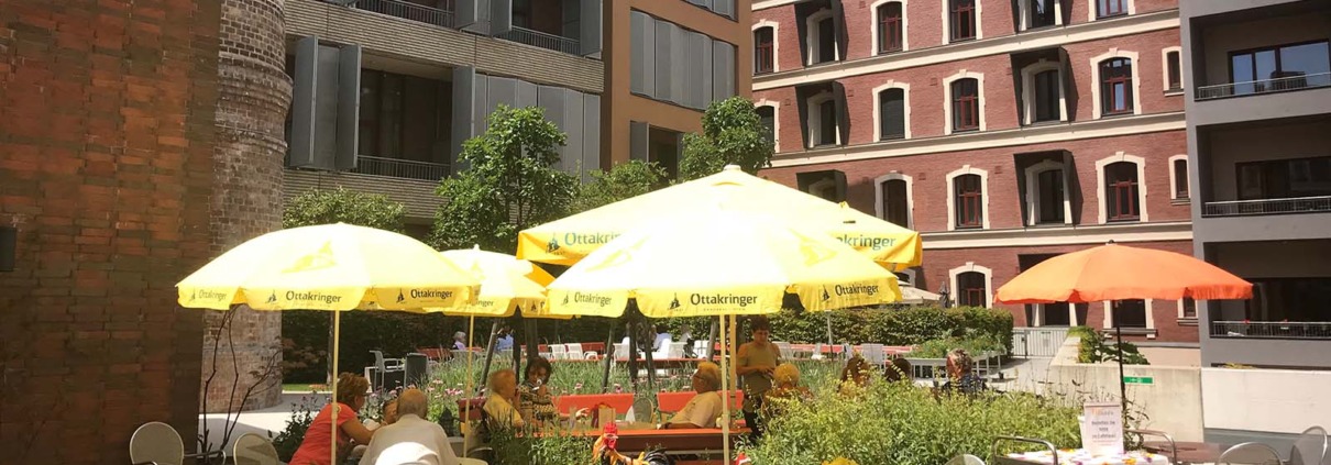 Bewohner*innen unter Sonnenschirmen in der Pflege Innerfavoriten