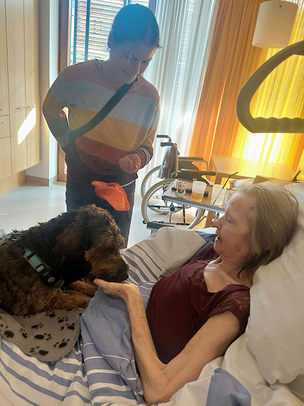 Tiertherapeutin Sophia mit ihrem Hund Bruno am Bett einer Bewohnerin