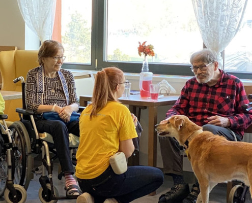 Therapeutin mit Hund vor sitzenden Bewohner*innen in der Pflege Meidling